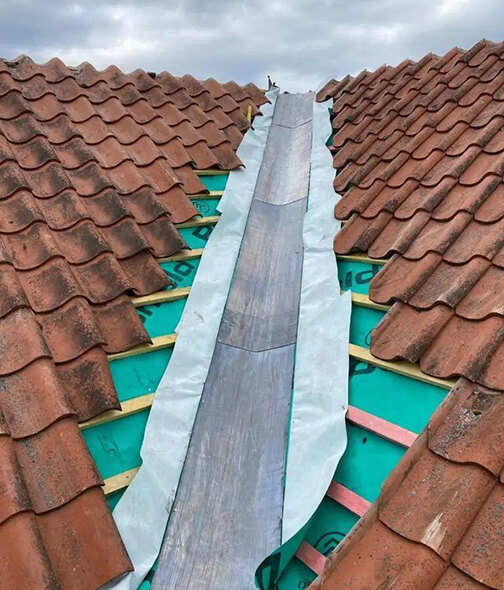 New valley lining fitted between two clay tiled roof slopes